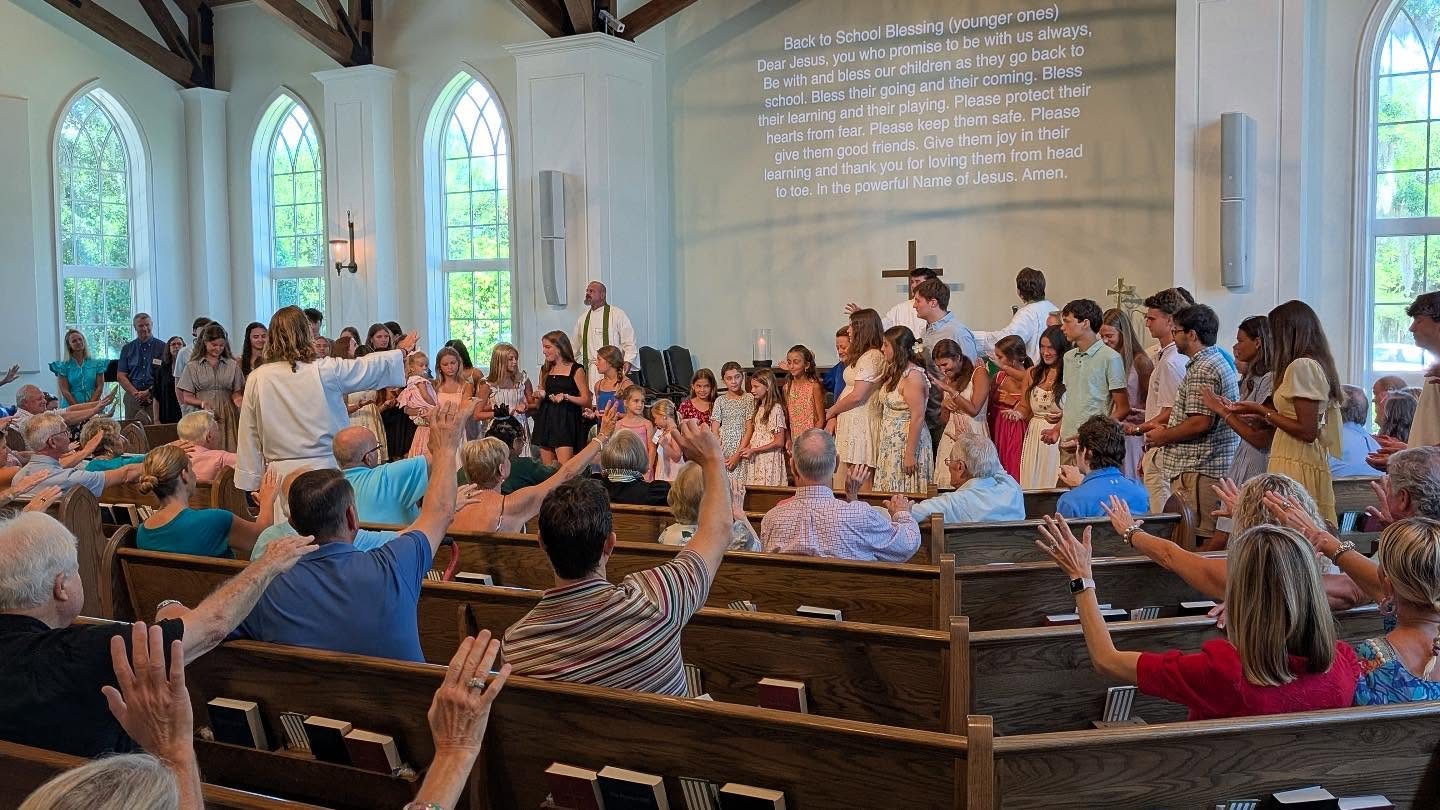 The congregation raises their hands to bless the children and students gathered at the front for the Back to School Blessing