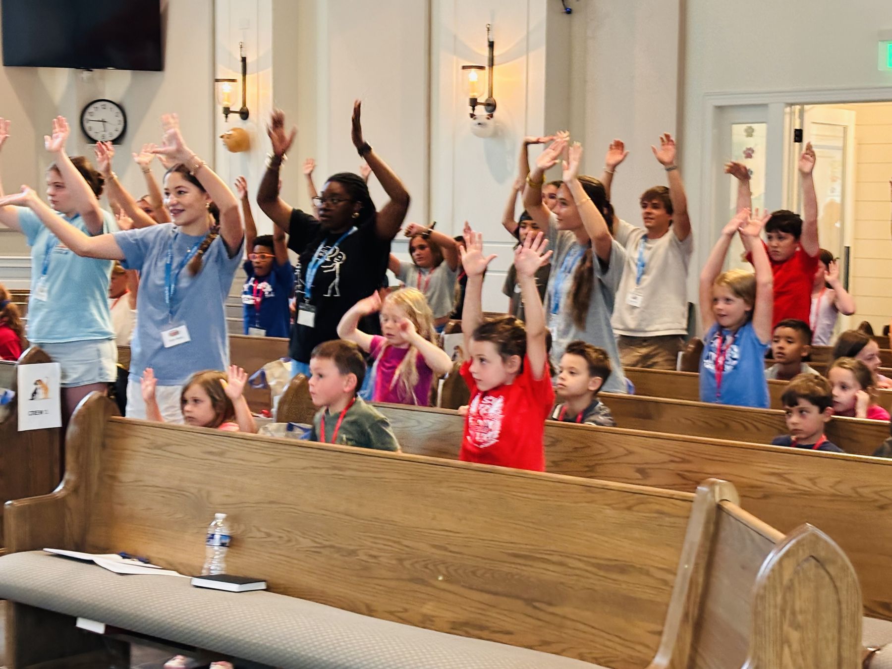 Children and teen leaders raising their hands during worship at Kids Blast in the sanctuary
