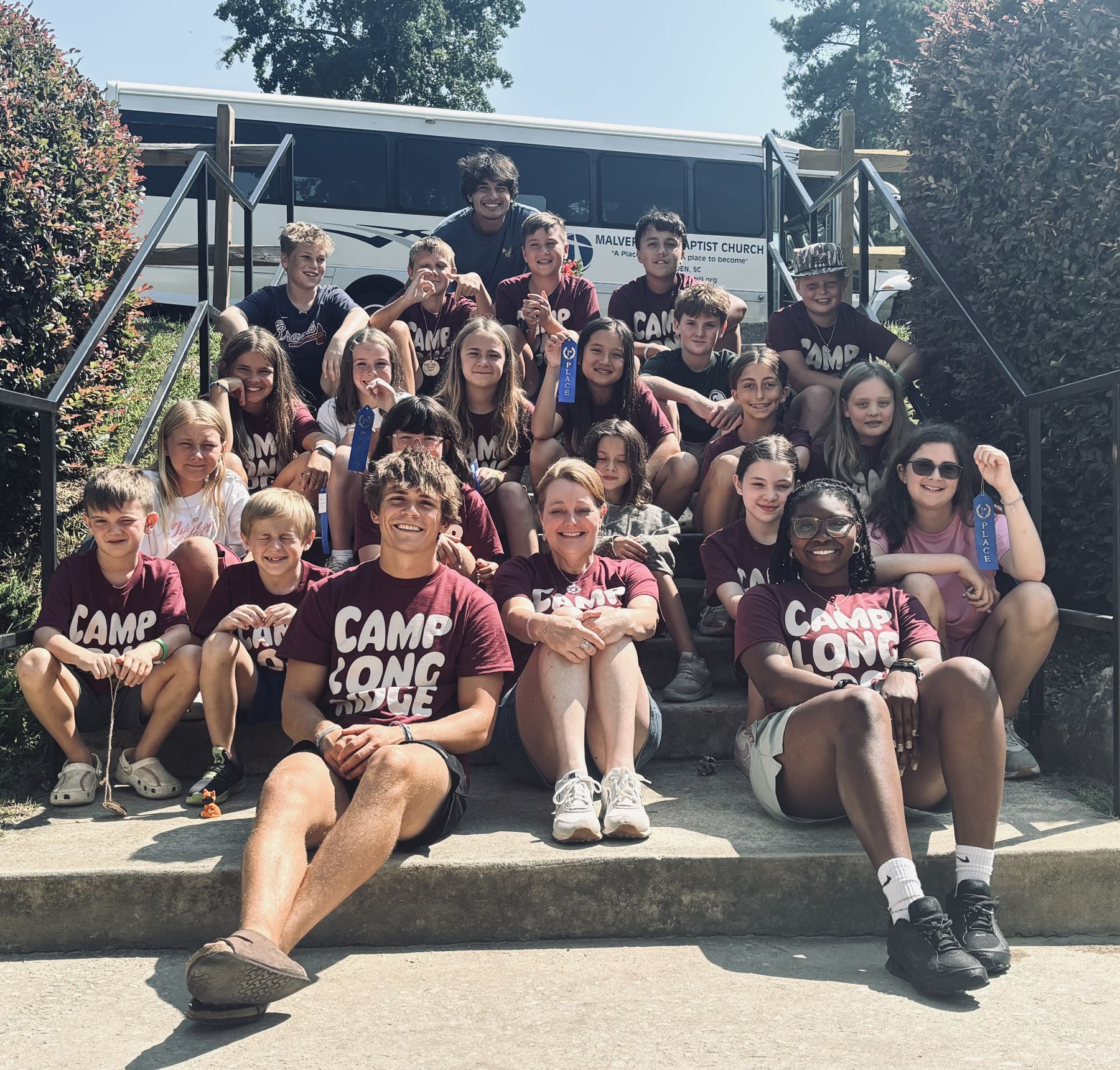 Abbey Kids campers and leaders in Camp Longridge T-shirts gathered on the steps, some holding first-place ribbons